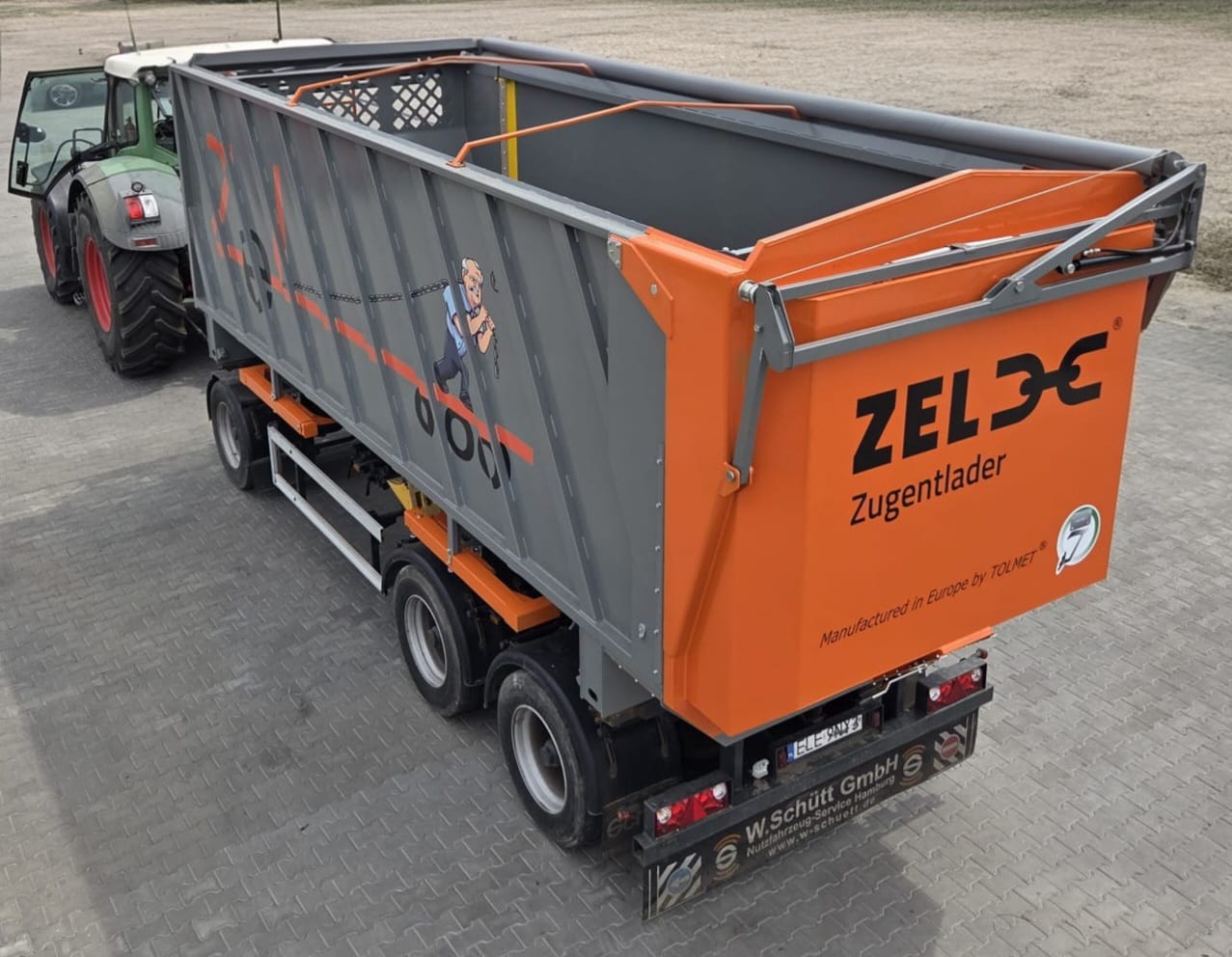 ZEL-Zugentlader am Traktor: Container mit oranger Heckklappe und ZEL-Schriftzug.